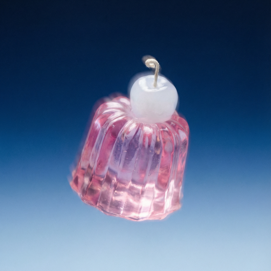 Pink glass ornament with white top on a blue gradient background